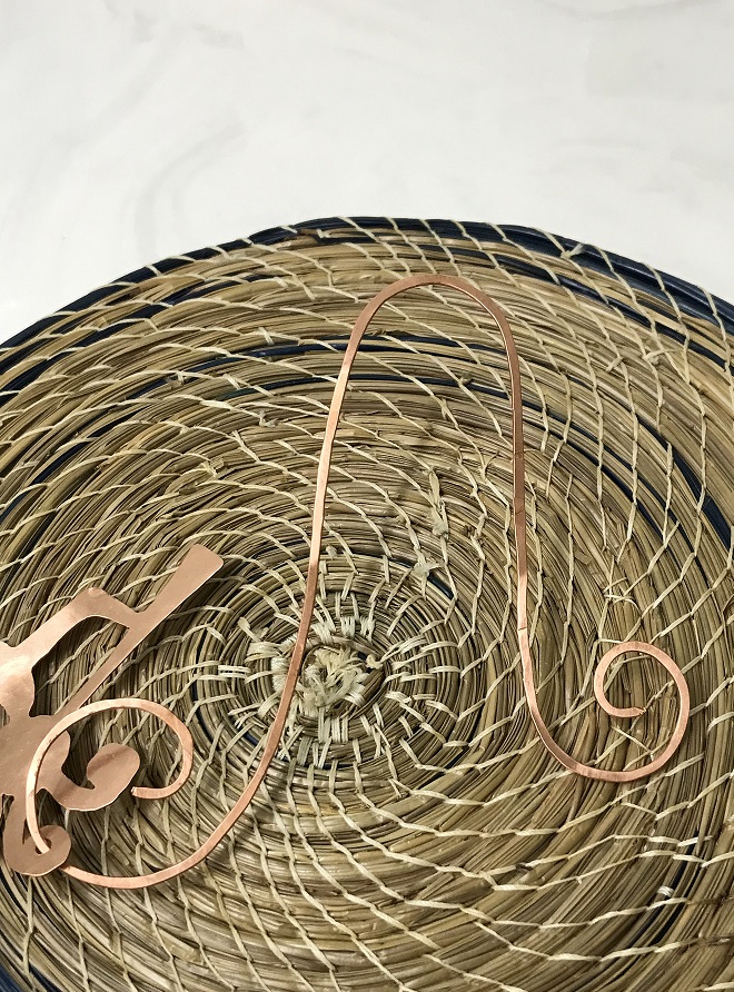 Copper halnger that goes with the Kokopelli Copper Ornament. The hanger is on a blue and tan basket background.